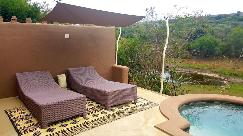 A poolside area with two wicker lounge chairs and a small hot tub.