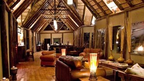 Um interior acolhedor e rústico com vigas de madeira, móveis de couro e uma atmosfera aconchegante.