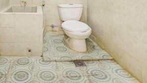 Uma casa de banho pequena e simples, com sanita, lavatório e janela.