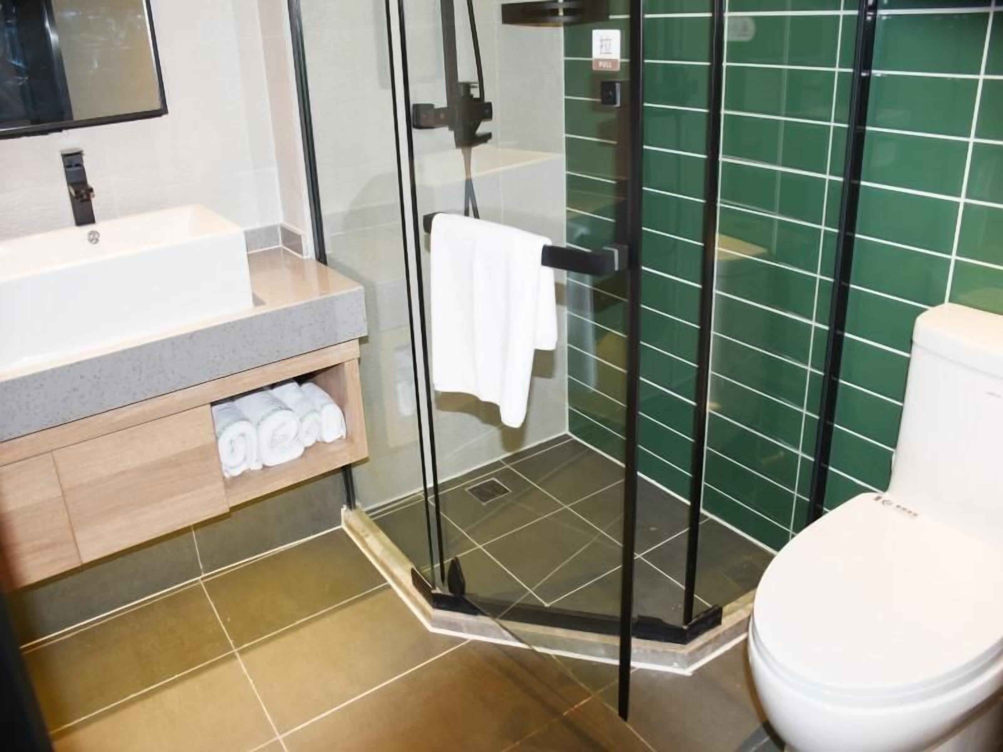 Ein modernes Badezimmer mit einer Duschkabine aus Glas, einem weißen Waschbecken und einer Toilette.