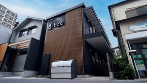 A modern building with a prominent 'boxi' sign, featuring a mix of wooden slats and metal panels, and a visible mail slot. - Boxi Hakata 1 -Sleep Hotel- (Fukuoka)