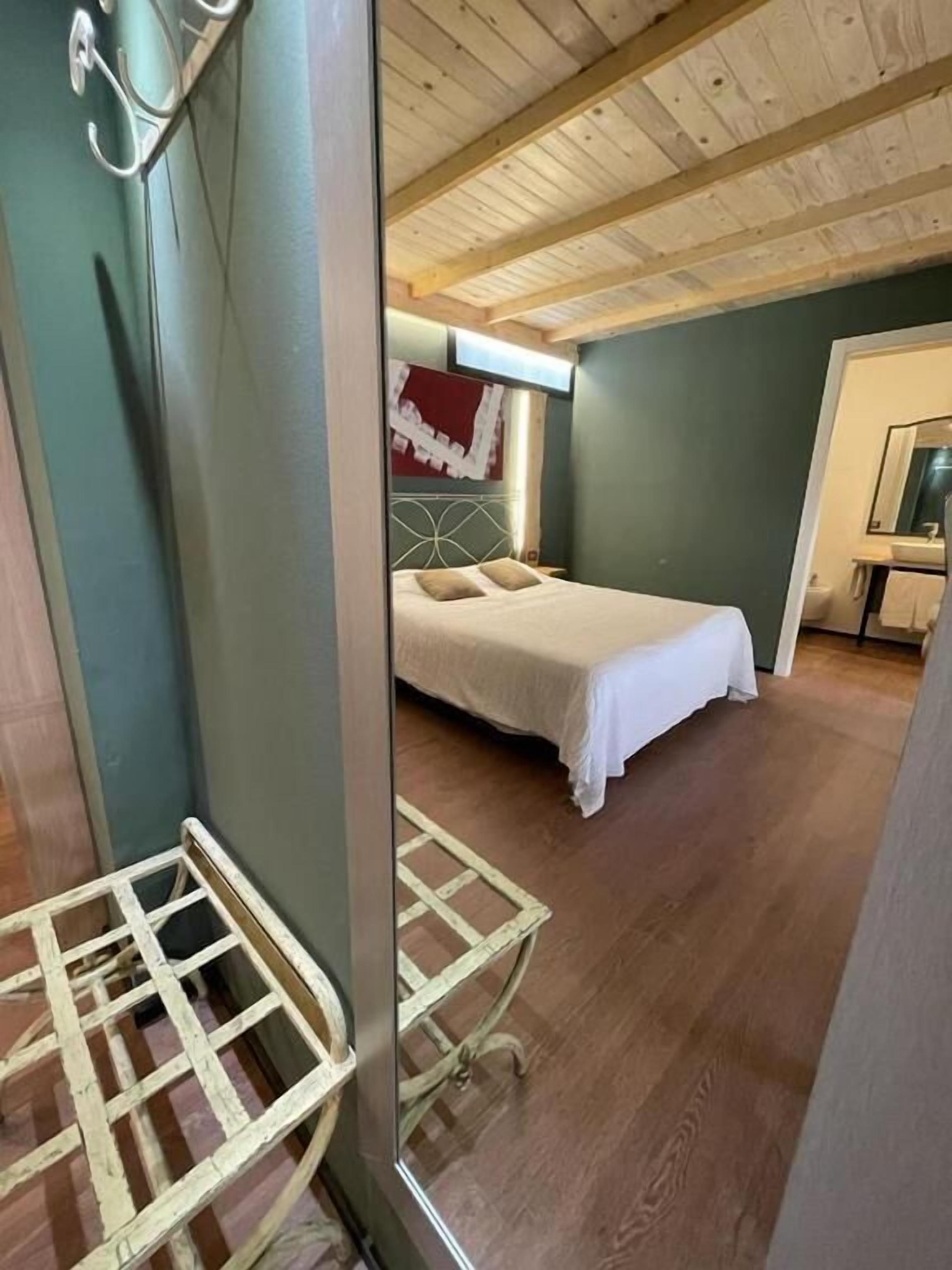 Ein Schlafzimmer mit einem Bett, einem Kopfteil, einer Holzbalkendecke und einem kleinen Tisch.
