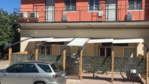En bygning med flere etager, altaner, ventilationsanlæg og en parkeringsplads med en bil.