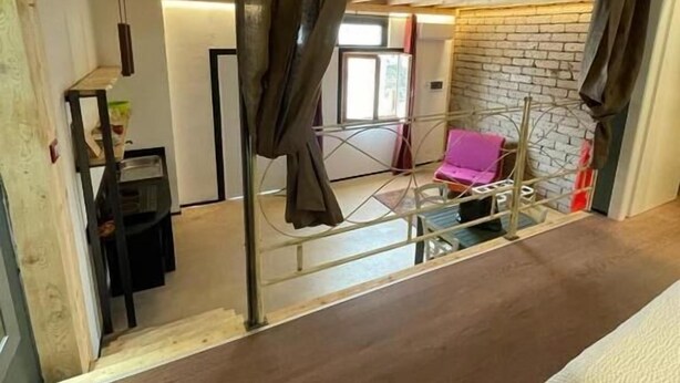 A room with a bed, a chair, a table, and a curtain. - GARBINI AT THE LOFT F FAIR (Verona)