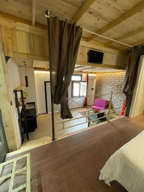 A room with a bed, a chair, a table, and a curtain. - GARBINI AT THE LOFT F FAIR (Verona)