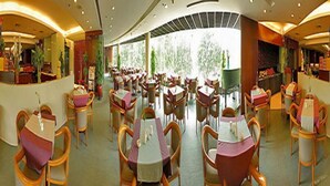 A spacious dining area with multiple tables and chairs, a reception desk, and large windows allowing natural light. - Star Hotel (Guangzhou)
