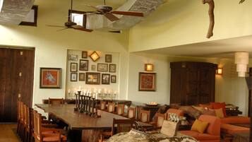 A spacious living room with a high ceiling, a dining area with a long table, and a cozy seating area with a vintage car model.