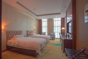 Habitación de hotel con dos camas, un escritorio, una silla y un televisor.