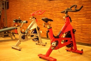 Three stationary bikes in a room with a wooden wall. - Shuiyuntian Leisure Hotel (Jinshazhou) (Foshan)