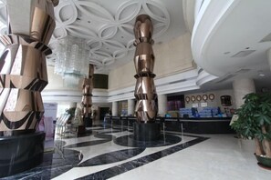 A lobby with a marble floor, large metallic sculptures, and a reception desk. - Shuiyuntian Leisure Hotel (Jinshazhou) (Foshan)