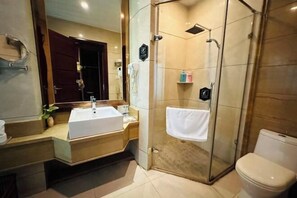 Un baño moderno con ducha de vidrio, lavabo blanco y retrete.