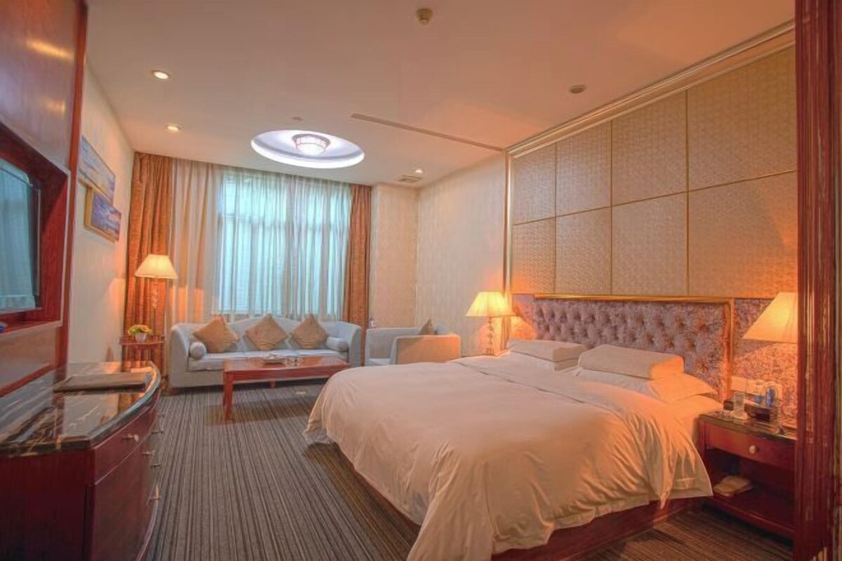 Una habitación de hotel con una cama grande, un sofá, un escritorio y una lámpara.