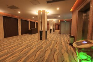 A hotel corridor with patterned carpet, a reception desk, and a digital information kiosk. - Shuiyuntian Leisure Hotel (Jinshazhou) (Foshan)