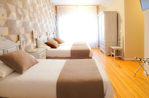 Una habitación de hotel con dos camas, un armario, un escritorio y una silla.