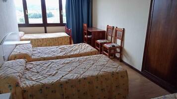 A room with three beds, a desk, and a chair.