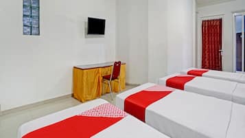 A hotel room with a bed, a desk, a chair, a TV, and a door.