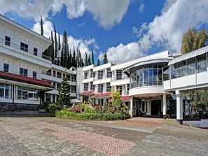 A courtyard with a cobblestone ground, surrounded by buildings with balconies and large windows, under a partly cloudy sky. - OYO 90028 Hotel Victory (Batu)