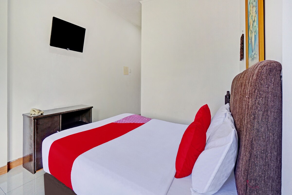 Une chambre d’hôtel avec un lit, un bureau, une chaise, une télévision et un tableau au mur.