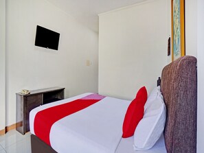 Quarto de hotel com cama, escrivaninha, cadeira, televisão e um quadro na parede.