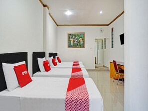 A hotel room with four beds, each with a red and white patterned bedspread, a clock on the wall, and a painting above the door. - OYO 90028 Hotel Victory (Batu)