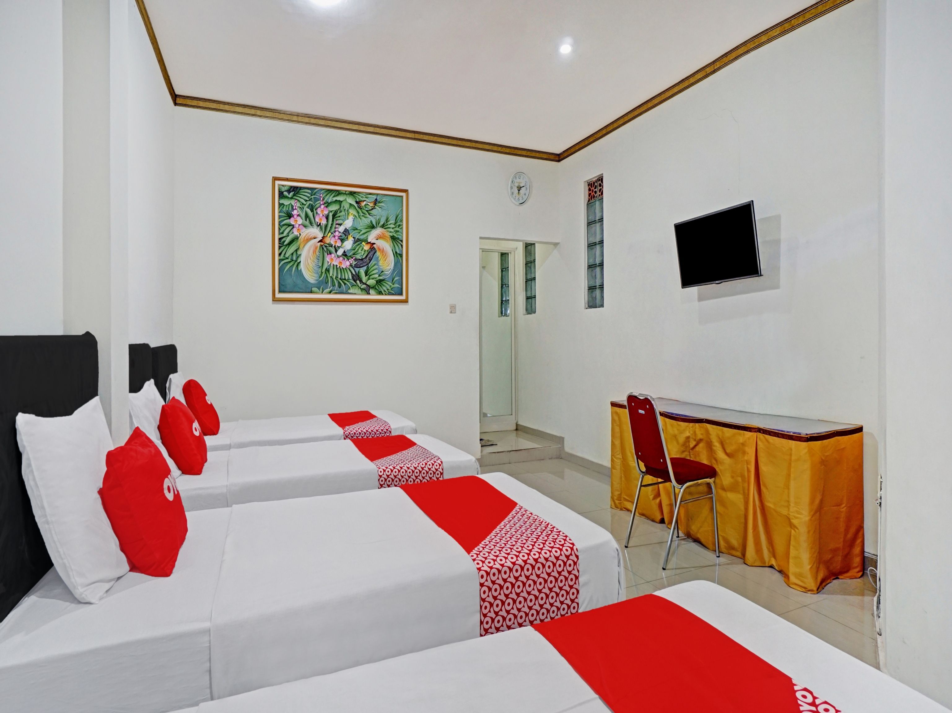 A hotel room with two beds, a desk, a chair, a TV, and a painting on the wall.