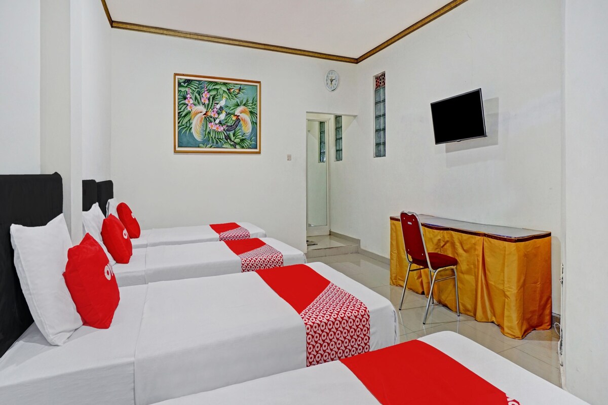Une chambre d’hôtel avec deux lits, un bureau, une chaise, une télévision et un tableau au mur.