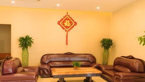 Una sala de estar con un sofá de cuero marrón, una mesa de centro de madera y dos plantas en macetas.