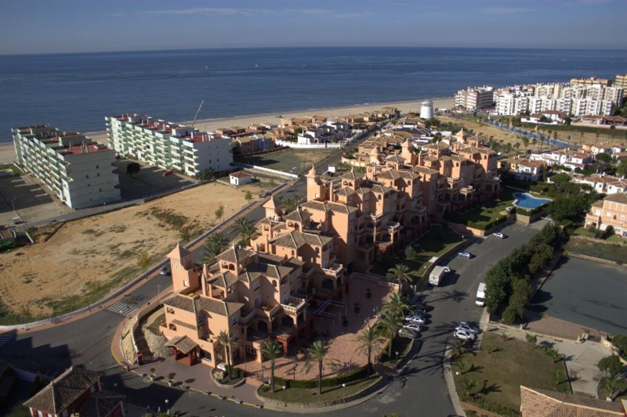 Un pueblo costero con un complejo de edificios históricos, una playa y modernos rascacielos.
