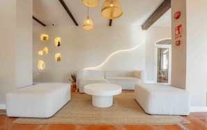 Una sala de estar moderna con un sofá blanco, una mesa de centro redonda e iluminación original montada en la pared.