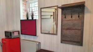 A room with a red refrigerator, a microwave, a small wooden bench, a mirror, and a wooden door. - Hübsches Zimmer mit Eigenem Bad und Kochecke, Gute Verkehrsanbindung (Swisttal)