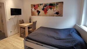 A bedroom with a bed, a desk, a chair, a flat-screen TV, and a world map artwork on the wall. - Hübsches Zimmer mit Eigenem Bad und Kochecke, Gute Verkehrsanbindung (Swisttal)