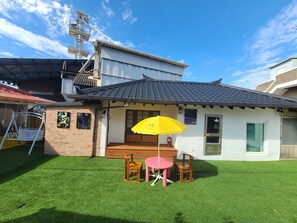 A small house with a tiled roof, a brick exterior, and a small porch with a yellow umbrella. - Sangjuhanok (Sangju)