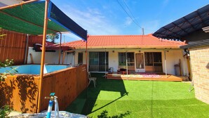 Un patio trasero residencial con piscina, césped artificial y una terraza de madera.