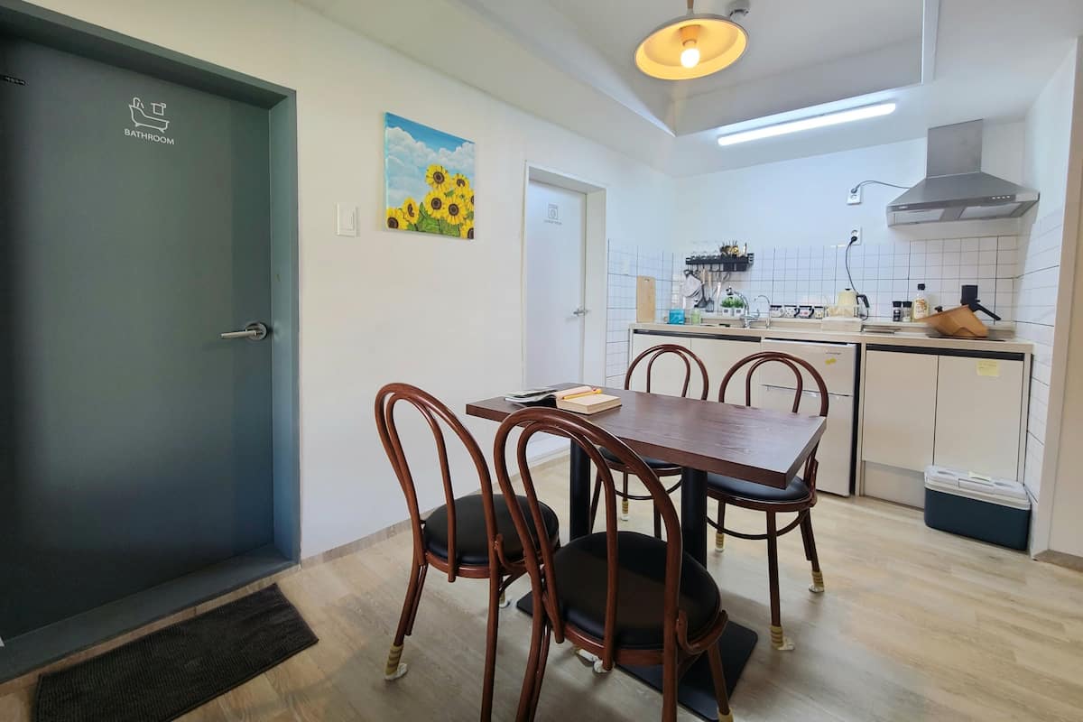 Une cuisine de taille réduite, avec des carreaux blancs, une table à manger en bois et des chaises.