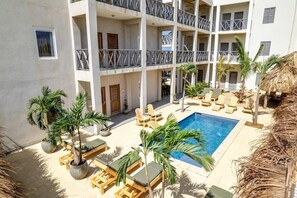 A multi-story hotel with a pool area, outdoor seating, and palm trees. - Belnem Breeze Dushi Bida with a refreshing shared pool and views of the salt pier and the sea (Kralendijk)