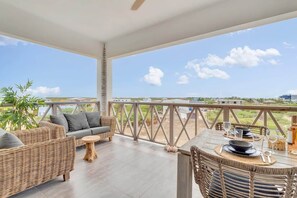 Een overdekt terras met rieten meubels, een eettafel voor twee personen en uitzicht op het landschap.