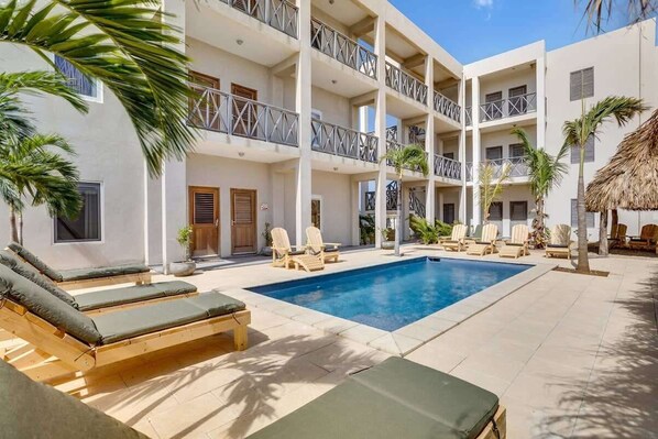 A hotel with a pool area, multiple balconies, and lounge chairs.