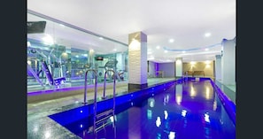 Relax by the indoor pool, surrounded by a fitness center and sleek architecture.
