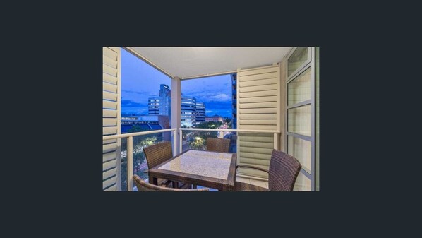 Enjoy the city view from this balcony with a glass railing and wicker chairs.