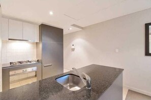 Enjoy cooking in this well-equipped kitchen with a granite countertop, stainless steel sink, and oven.