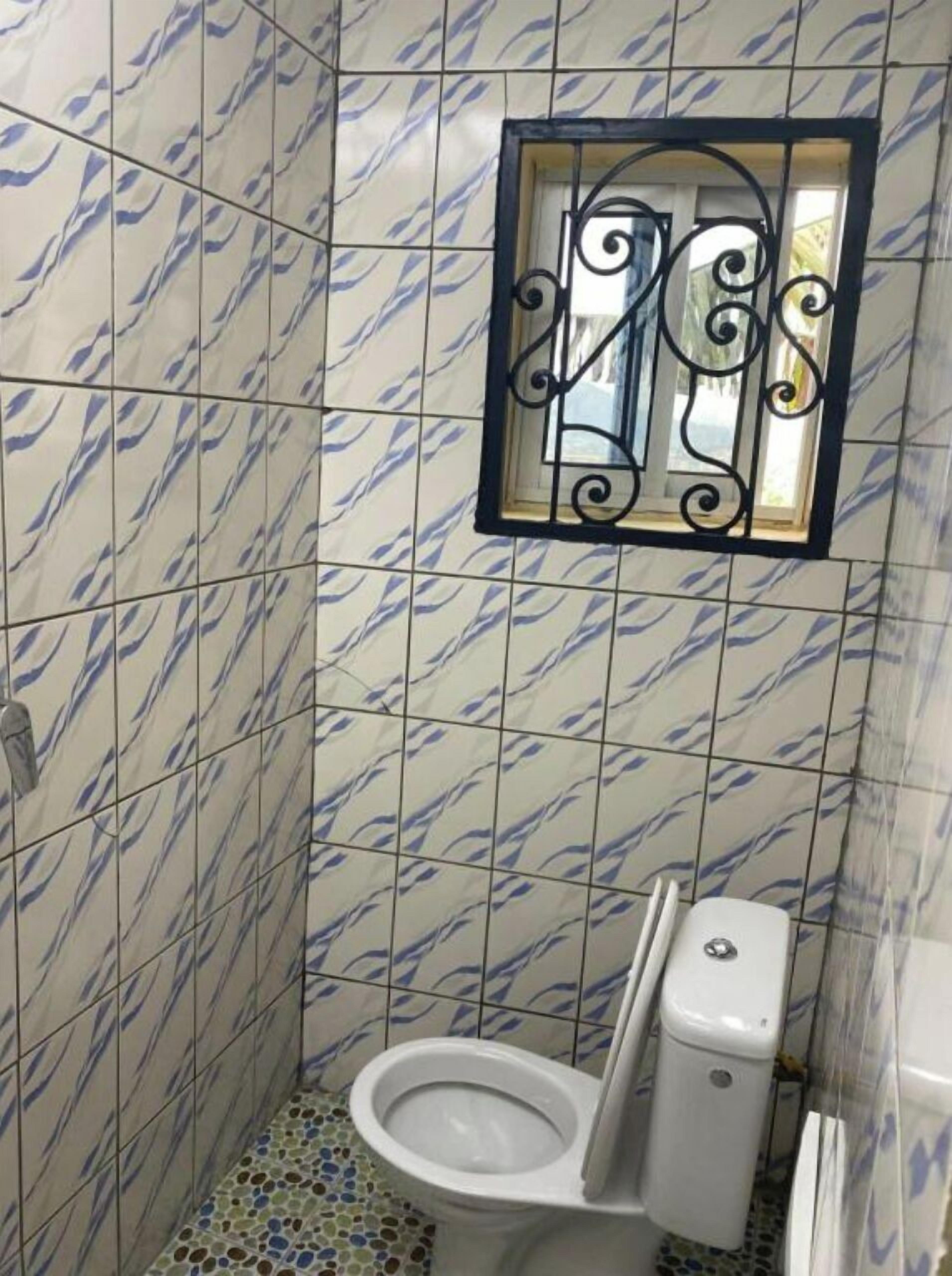 Un bany amb vàter, bidet i una petita finestra amb un emmarcament metàl·lic decoratiu.