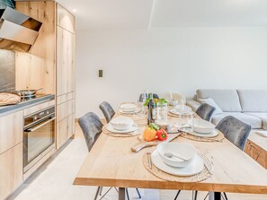 Un espace repas moderne avec une table en bois, dressée pour six personnes, entourée de chaises à revêtement gris.