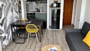 A compact living space with a dining area, kitchen, and seating area. - Appt Centre de Courseulles - 100m de la Plage (Courseulles-sur-Mer)