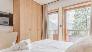 A bedroom with a wooden wardrobe, a bed with white bedding, and a balcony with a view of trees and mountains. - Champagny en Vanoise: Apartment 6 people, 3 rooms, balcony (Champagny-en-Vanoise)