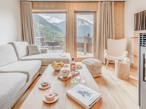 Relax in a cozy seating area with a sofa, armchair, and coffee table, surrounded by a scenic mountain view.