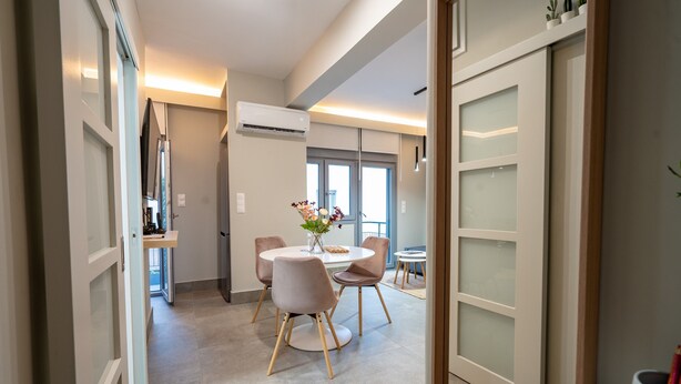 Un espace repas moderne avec une table ronde, quatre chaises et un vase rempli de fleurs.