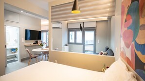 Une chambre d’hôtel moderne dotée d’un grand lit, d’un coin repas avec une table et des chaises, d’une télévision et d’un balcon offrant une vue agréable.