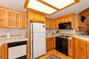 A kitchen with wooden cabinets, a white refrigerator, a microwave, a stove, and a dishwasher.