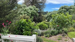 Un jardín con diversas plantas y una cerca de madera blanca.