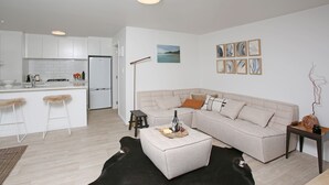 A modern living room with a sofa, ottoman, and a black leather rug. - Garden apartment Self-contained luxury just 5 mins walk to Village!  (Matakana)
